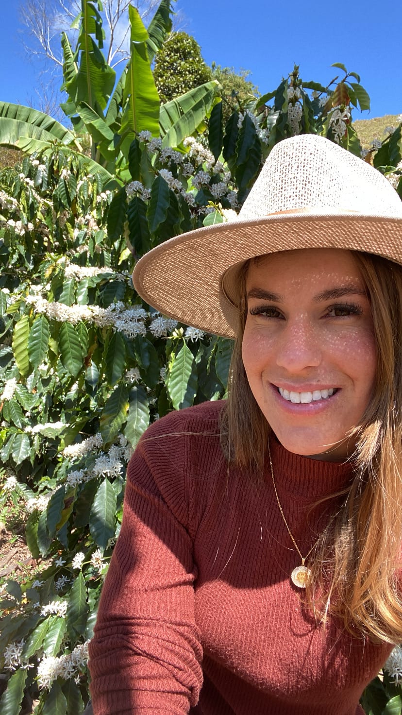 Produtora sorrindo diante da florada do café